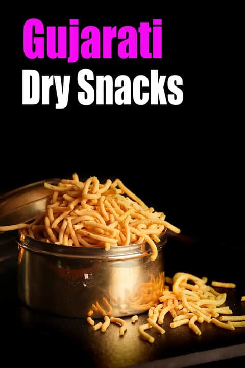 Gujarati dry snacks featuring crispy sev stored in a steel container, with some sev spilled beside it on a dark background, and the text “Gujarati Dry Snacks” displayed on the image.