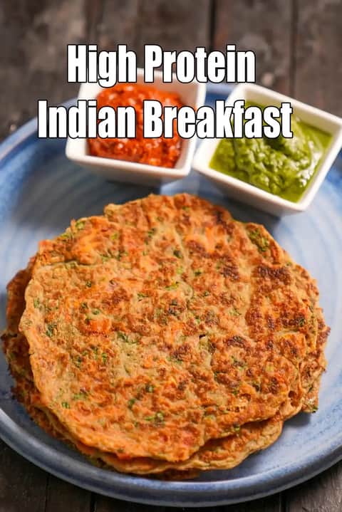 A top-down view of a stack of savory Indian pancakes (Chilla) served with green and red chutneys on a blue plate, with the text High Protein Indian Breakfast overlaid.