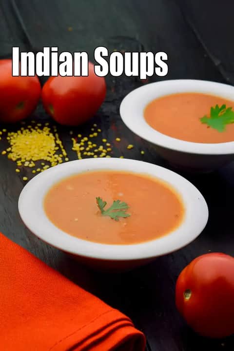 Two bowls of Indian tomato soup garnished with coriander leaves, placed on a dark wooden surface with fresh tomatoes, lentils, and an orange napkin, representing healthy Indian soups.