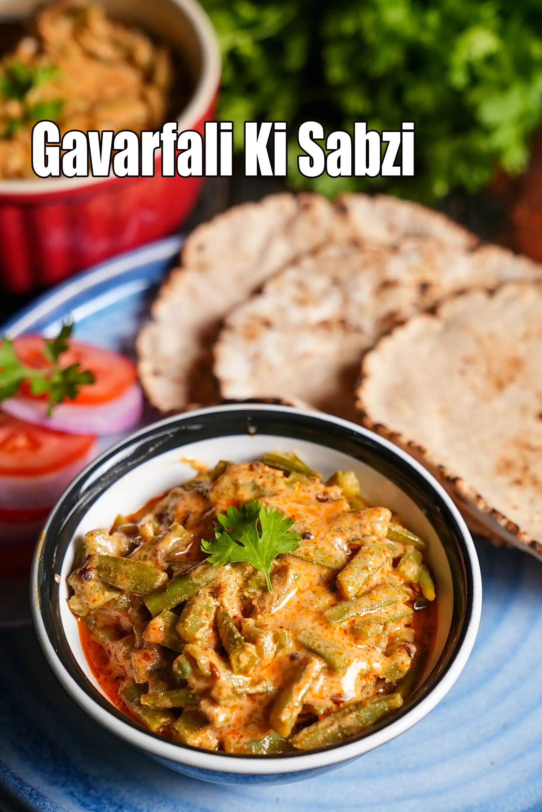 Gavarfali ki sabzi served in a bowl, made with cluster beans cooked in a creamy spiced gravy, garnished with fresh coriander, and paired with rotis, onion slices, and salad on the side.