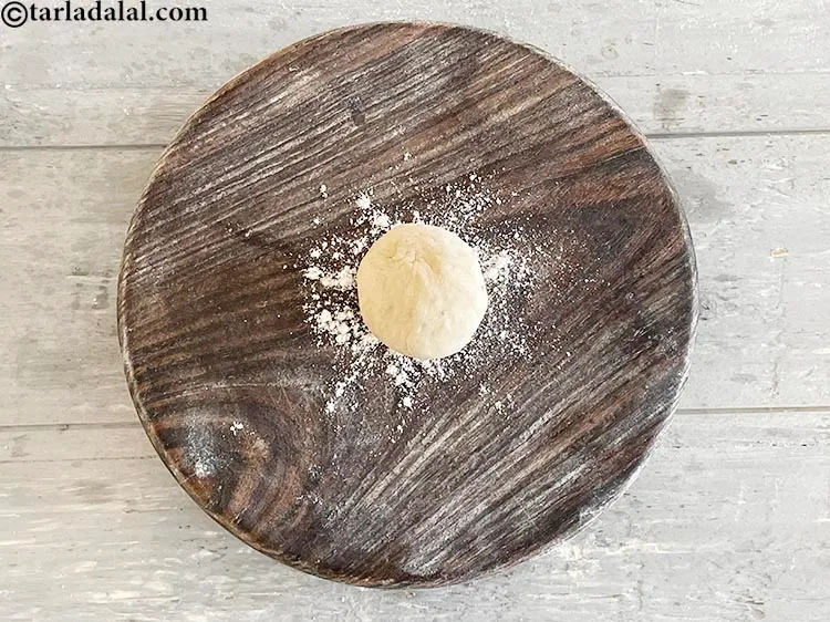 Step 16 – <meta charset="UTF-8" />Softly flatten the dough ball with a belan (roller).