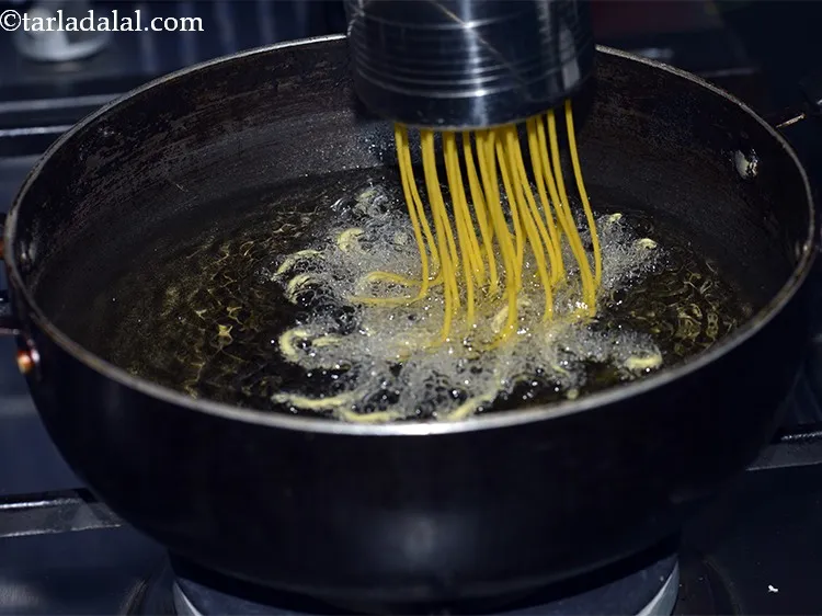 Step 43 – Press out thin strands of the sev in batches into the hot oil.