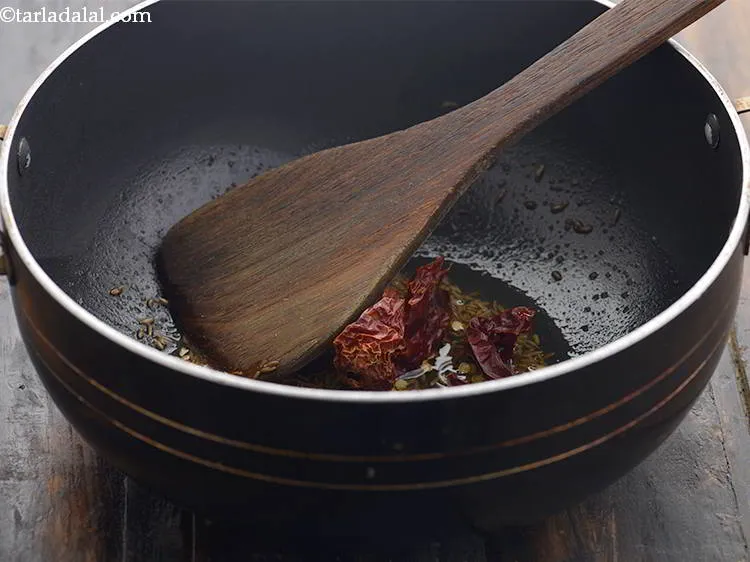 Step 8 – When the seeds crackle, add the dry red chillies.