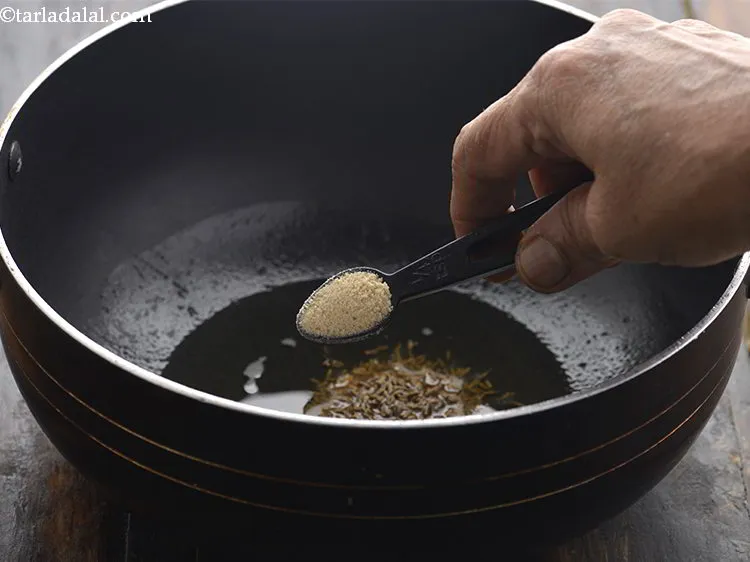 Step 7 – When the oil is moderately hot, add the cumin seed and asafoetida.