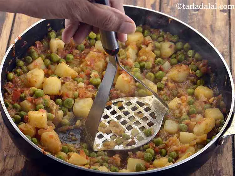 Step 17 – Mash 2 to 3 pieces of potatoes in the pan to thicken the <strong>aloo matar …