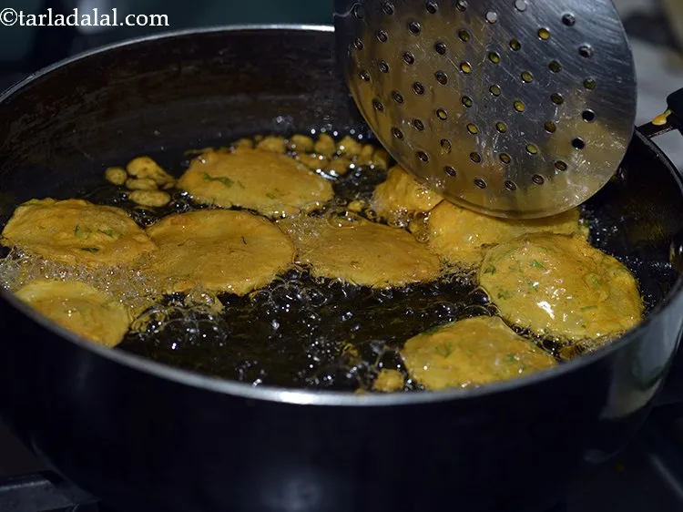 Step 21 – Deep-fry around 8-9 <strong>aloo pakora</strong> at a time till they turn golden brown in colour …