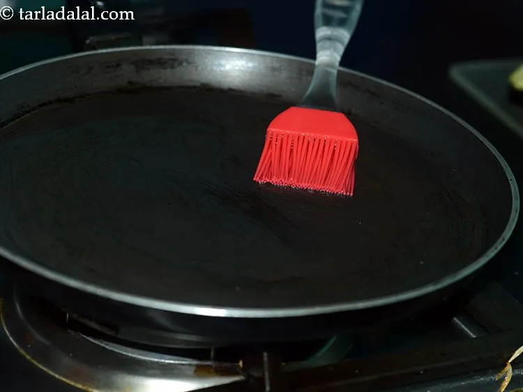 Step 10 – To cook <strong>baingan bhaja</strong>, heat a non-stick tava (griddle) and grease it with &frac12; tsp …
