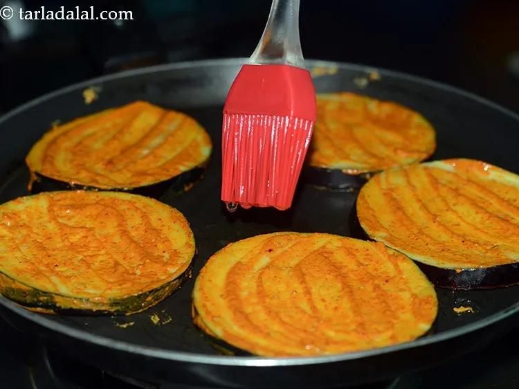 Step 12 – Drizzle &frac12; tsp of oil on and around the brinjal slices.