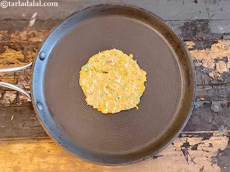 स्टेप 30 – इसके ऊपर १/४ कप घोल डालें और तवे को हल्का …