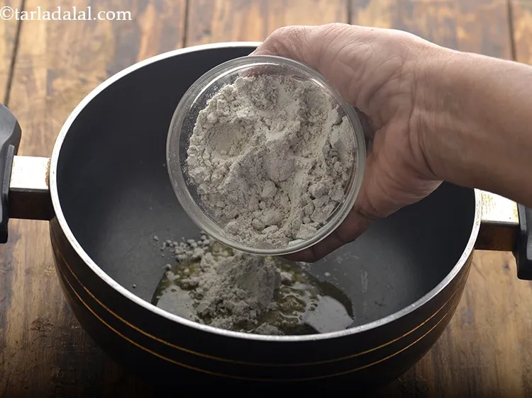 Step 11 – As the ghee melts, add bajra flour to it.