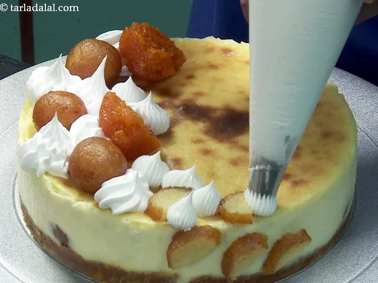 Step 26 – Decorate the <strong>baked gulab jamun cheesecake</strong> with whipped cream.&nbsp;