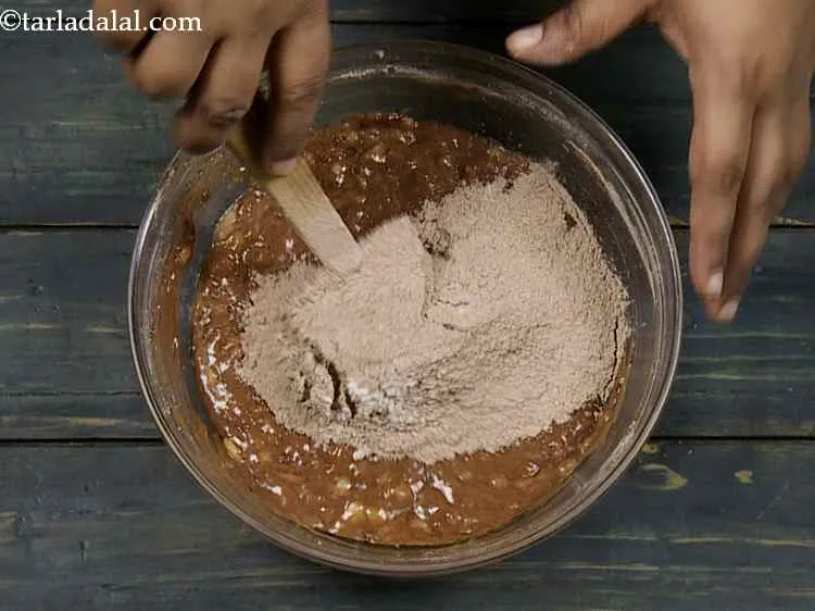 Step 13 – Gradually add the plain flour-cocoa powder mixture to the banana mixture and fold it using …