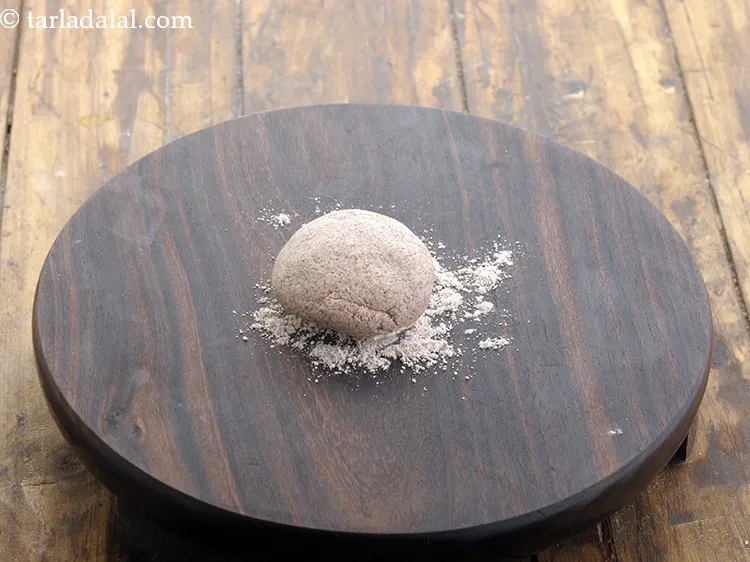 स्टेप 11 – आटे के भाग को हल्का सा चपटा करके रोलिंग बोर्ड …