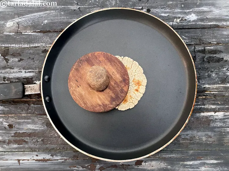 Step 39 – Continue cooking the bhakhri on a slow flame, while pressing with a khakhra press or …