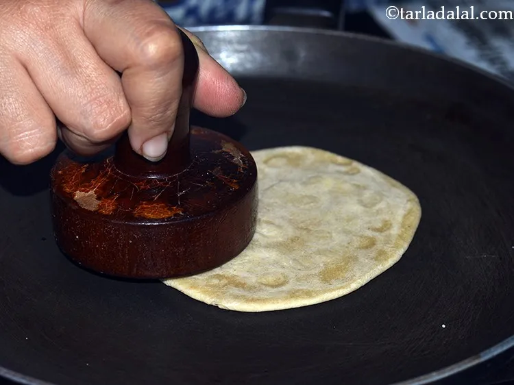 Step 16 – Keep flipping the <strong>Gujarati bhakri</strong> every 30 seconds to 1 minute and pressing it with …