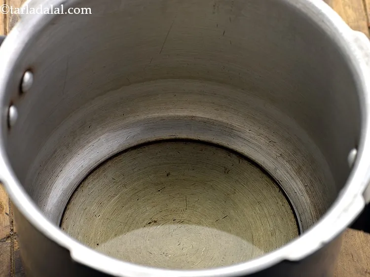 Step 18 – To prepare the<strong> Maharashtrian Bharli vangi</strong>, heat the oil in a pressure cooker.