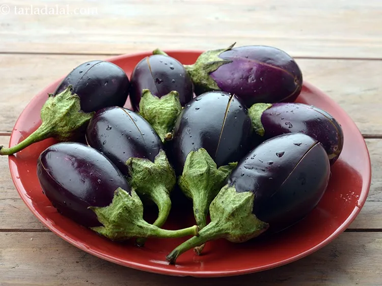 Step 15 – To prepare <strong>Maharashtrian Bharli Vangi</strong>, wash the brinjals and make criss-cross slit on each brinjal …