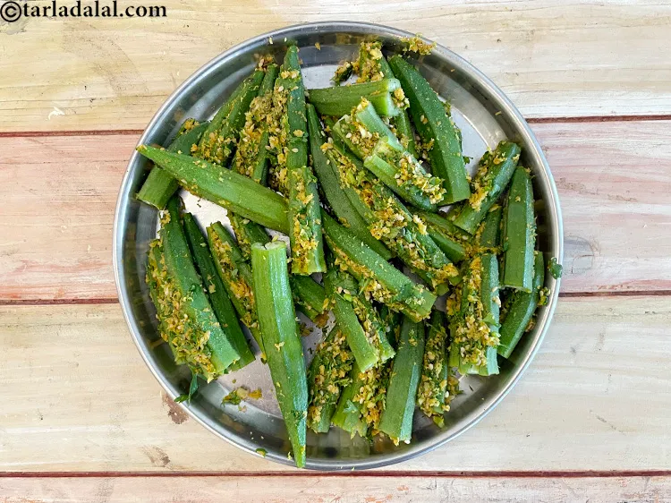 स्टेप 19 – प्रत्येक भिंडी में थोड़ा सा भरवां मिश्रण भरकर एक तरफ …