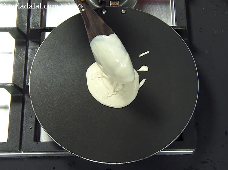 Step 10 – To prepare <strong>no fermentation bread dosa</strong>, heat a non-stick tava (griddle) and pour a ladleful …