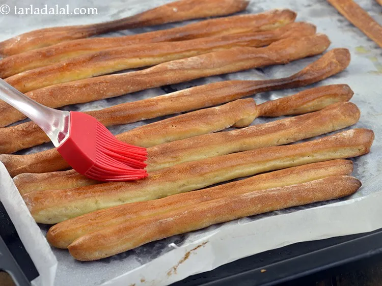 Step 21 – Brush all the bread sticks with the remaining &frac12; tsp of <a href="https://www.tarladalal.com/glossary-olive-oil-451i">olive oil</a> evenly …