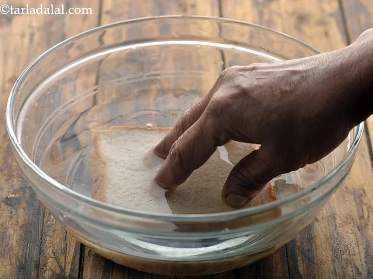 Step 2 – For making the quick and easy <strong>Bread Upma In Microwave</strong>, dip the bread slices one …