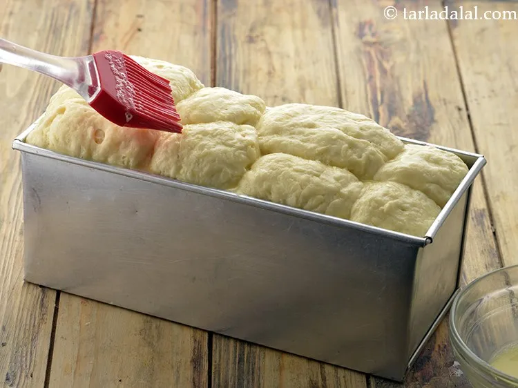 Step 46 – Remove the cling wrap from the loaf tin, and brush the egg yolk-milk mixture evenly …