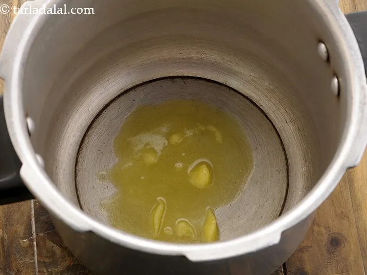 Step 9 – To prepare <strong>brown rice khichdi</strong>, heat ghee in a pressure cooker.