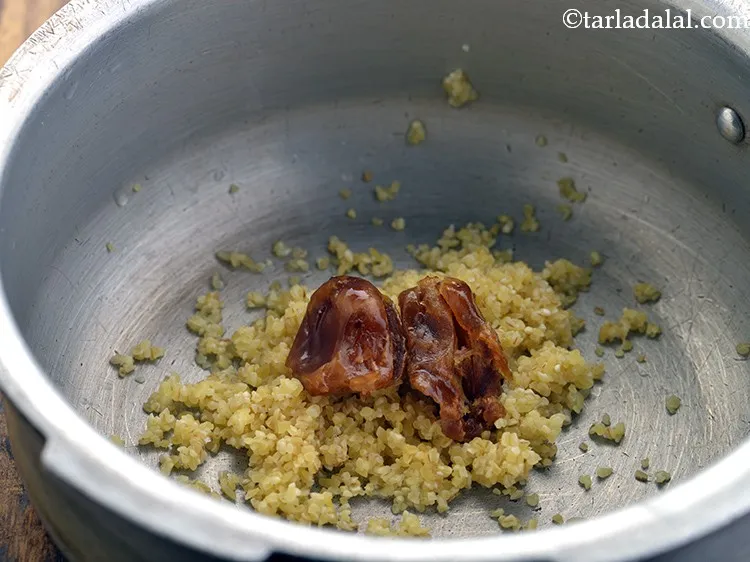 Step 12 – Add the dates in the pressure cooker along with the broken wheat (dalia).&nbsp;