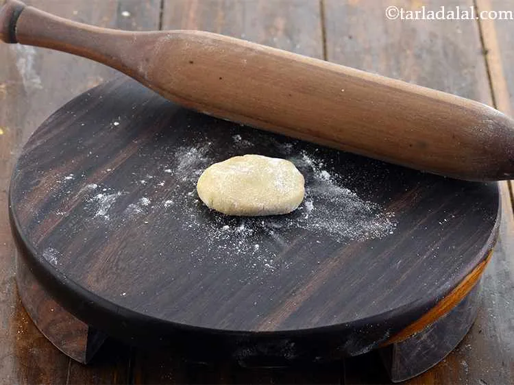 Step 13 – Take one ball of dough, flatten it, dip it in flour and dust off the …