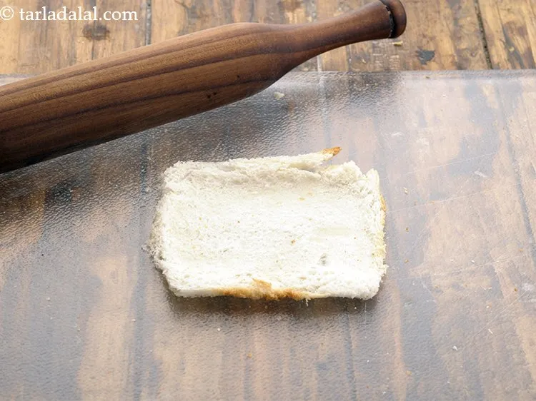 Step 14 – Roll a bread slice with the help of a rolling pin. Apply pressure evenly so, …