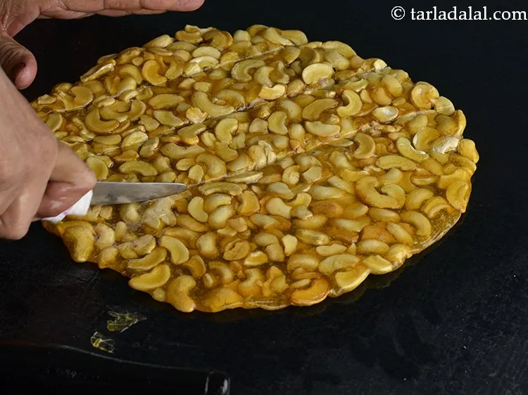 Step 15 – Immediately cut <strong>Kaju Chikki</strong> into 30 equal sized square pieces using a sharp knife and …