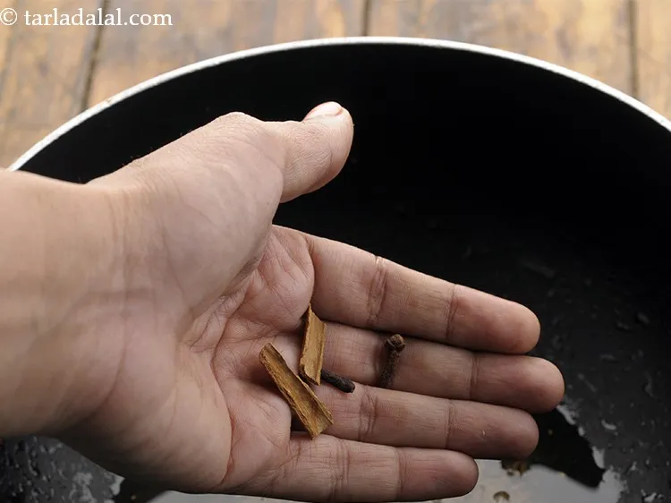 स्टेप 14 – जब बीज चटकने लगे, दालचीनी और लौंग डालें।