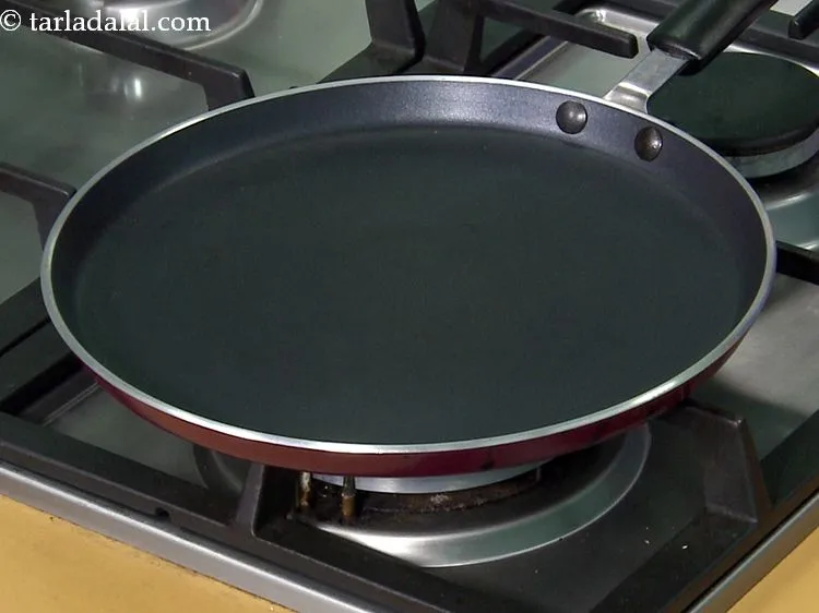 Step 25 – Take a flat non-stick tava (griddle) and heat it on a high flame. Reduce the …
