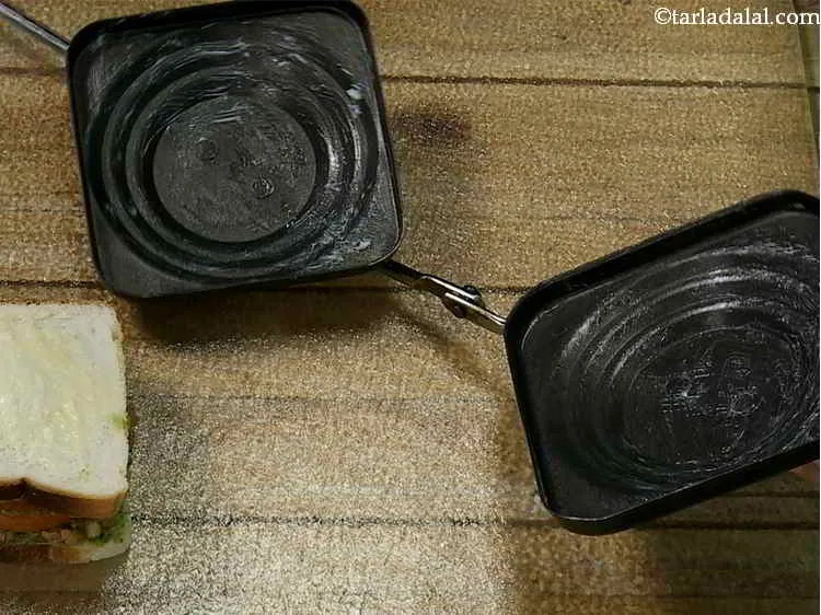 स्टेप 16 – सैंडविच टोस्टर को १/२ टीस्पून मक्खन का उपयोग करके दोनों …