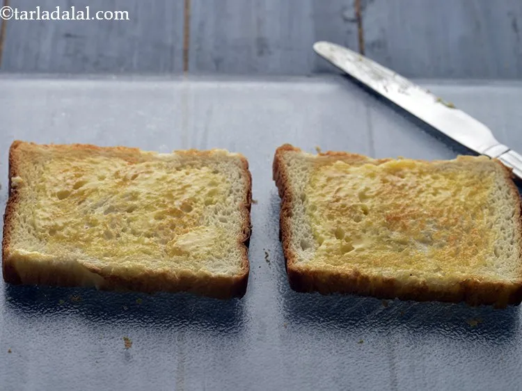 स्टेप 11 – २ टोस्टेड ब्रेड स्लाइस पर थोड़ा मक्खन लगाएँ।