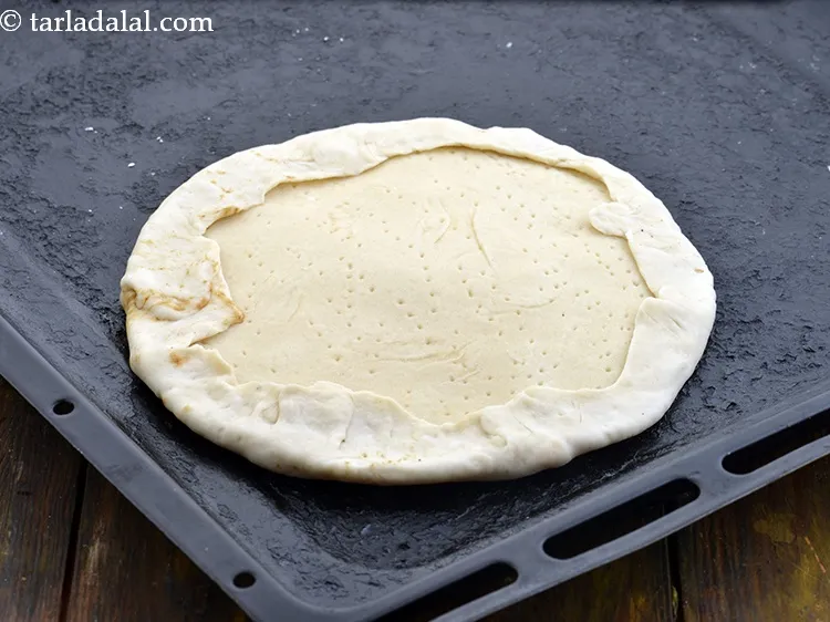 Step 27 – Place the half cooked pizza base over it and fold the sides of the bottom …