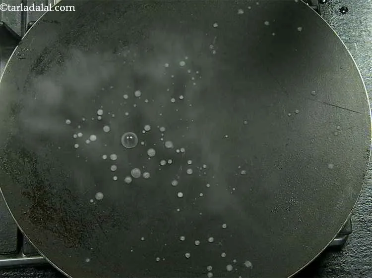 Step 10 – Sprinkle a little water on the tava (griddle).