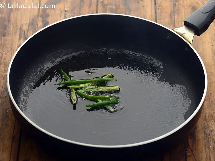 स्टेप 12 – तेल गरम होने पर इसमें हरी मिर्च डालें।