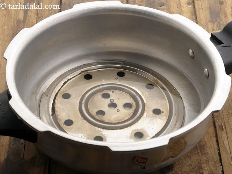 स्टेप 15 – प्रेशर कुकर में एक छोटा सा स्टैंड रखें, उसमें थोड़ा …