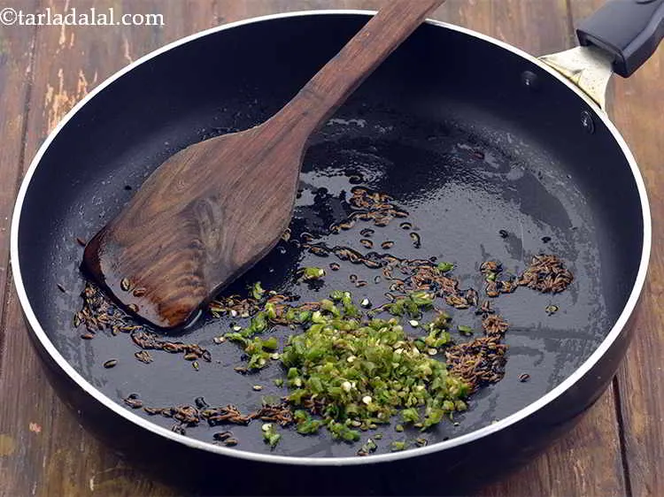 Step 24 – When the seeds crackle, add the green chillies for spice.