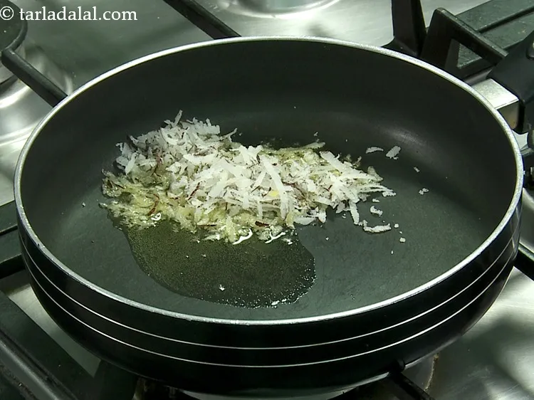 स्टेप 7 – जब घी गरम हो के पिघल जाए तो नारियल डालें।