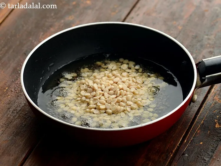 Step 14 – When the seeds crackle, add the urad dal.