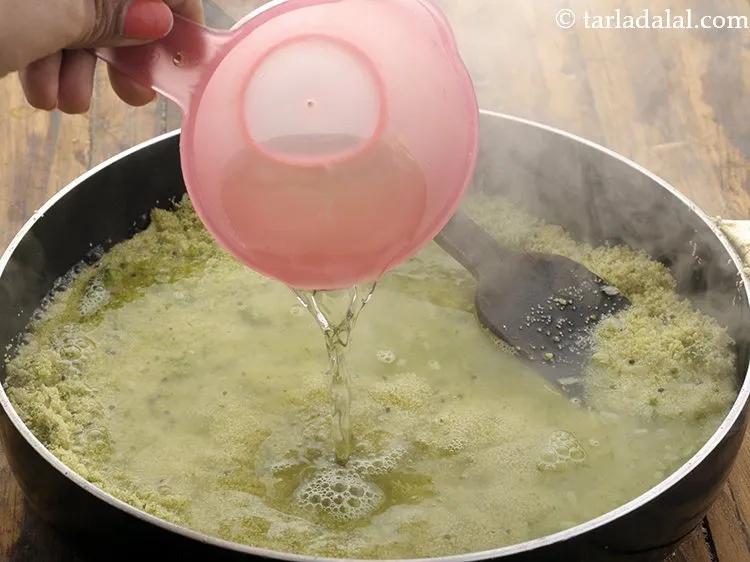 Step 18 – Add 2 1/2 cups hot water and cook the <strong>Coriander upma</strong> on a medium flame …