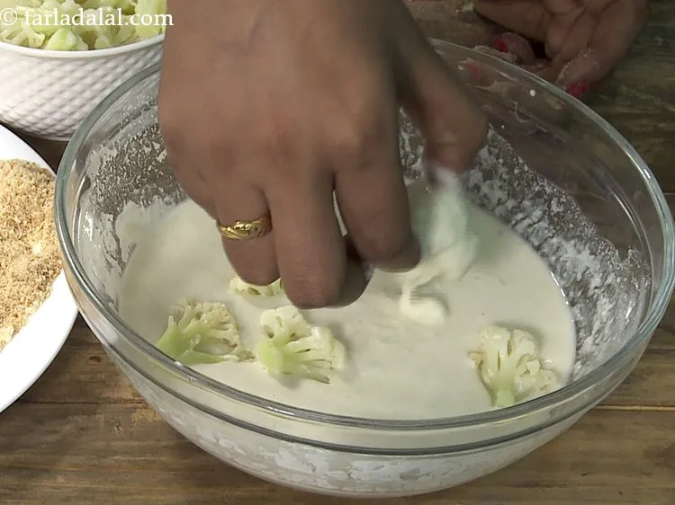 Step 16 – To prepare <strong>crispy fried gobi</strong>, dip the cauliflower florets one by one in the batter.