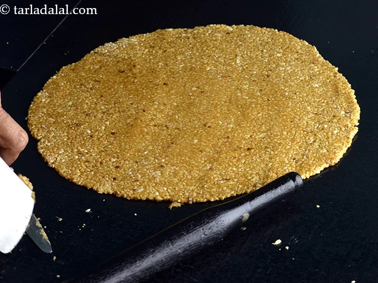 स्टेप 15 – <strong>क्रश मूंगफली की चिक्की</strong> को चिकना किए हुए रोलिंग पिन …