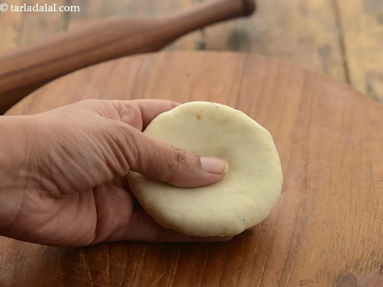 Step 34 – Gently press the center of the kachori with your thumb.