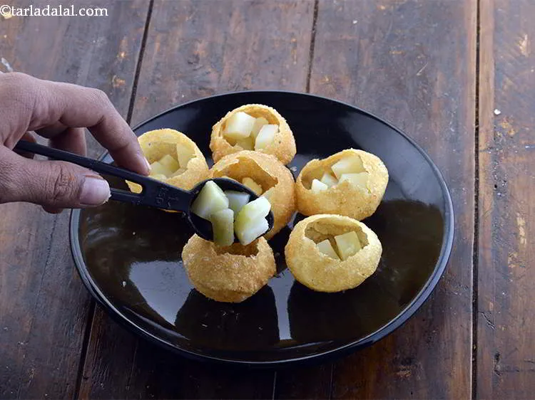 Step 11 – Stuff each <em>puri</em> with approximately 1 tsp of the boiled and chopped potatoes. One plate …