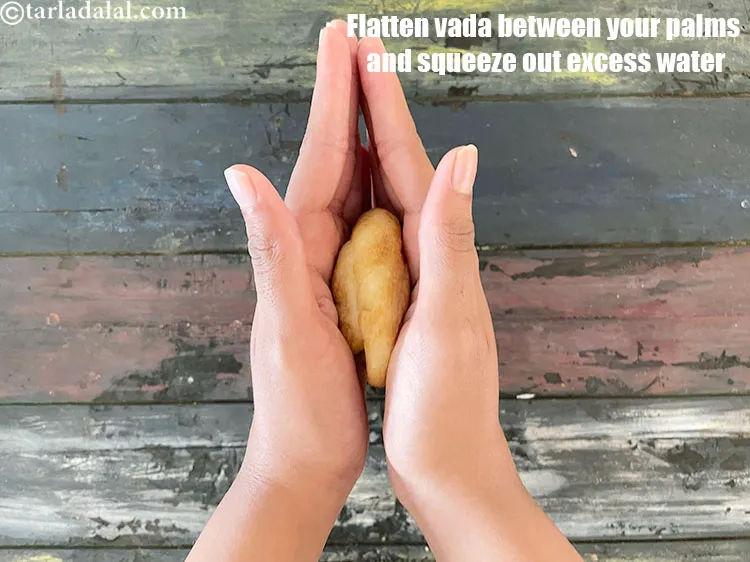 Step 31 – Squeeze out all the excess water from the vadas and flatten lightly between your palms.