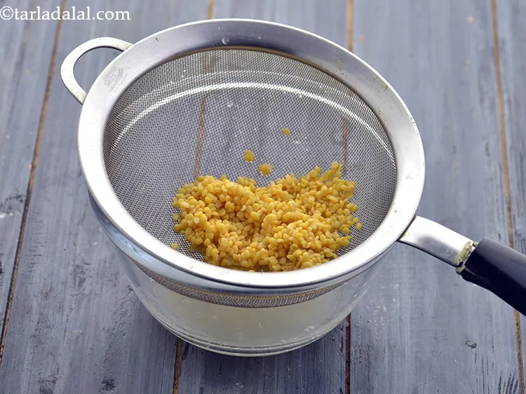 Step 10 – Drain the excess water using a strainer and discard it. Keep the moong dal aside.&nbsp;