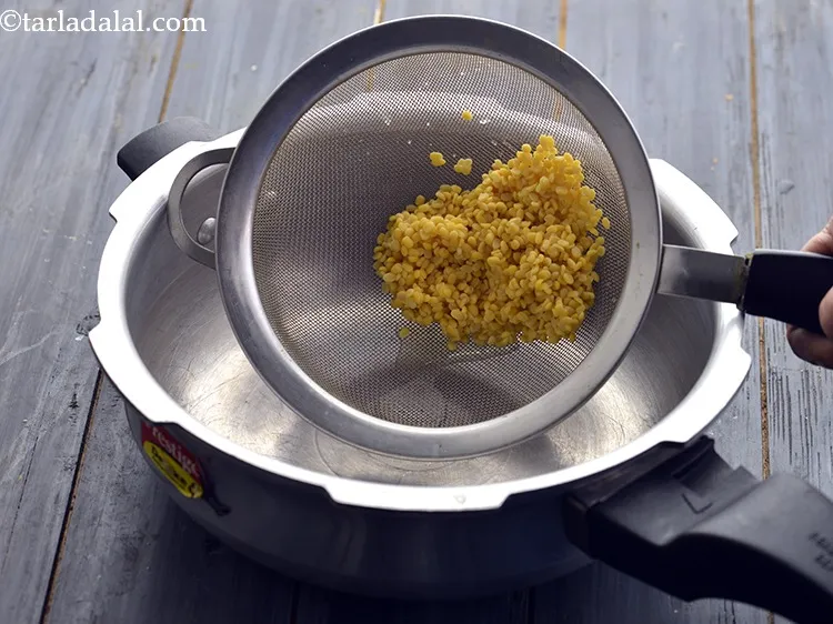Step 21 – Now transfer the washed yellow moong dal into a clean pressure cooker.&nbsp;